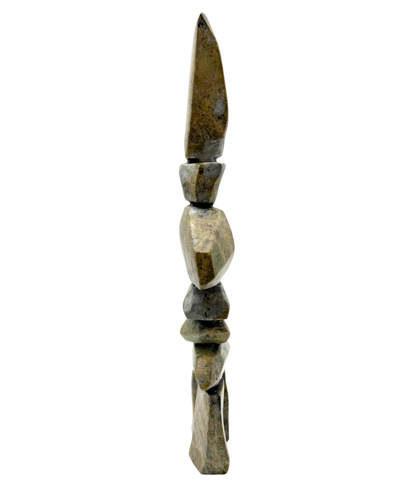 A tall inukshuk carved from greenish-brown stone.