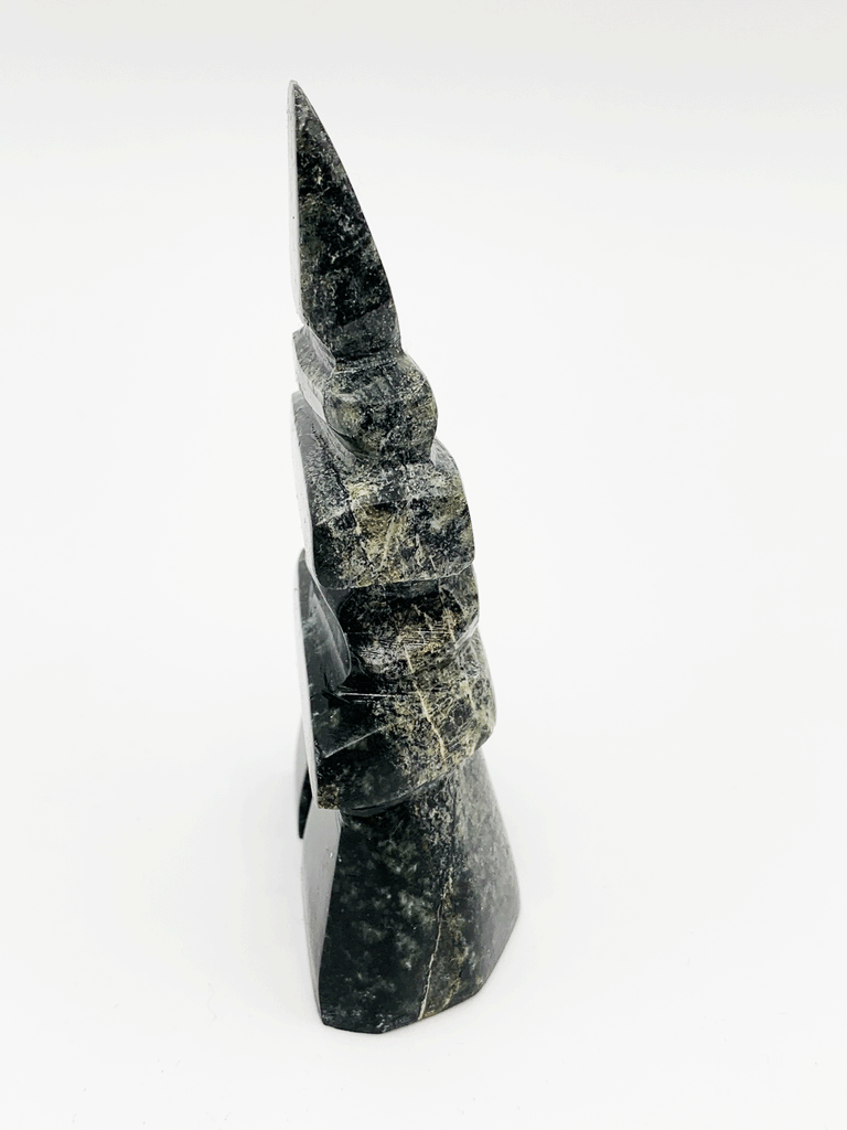 An inukshuk made of five single stones stacked on two legs. The shape very strongly suggests a person shape. The stone is brilliantly mottled green, brown, and black.