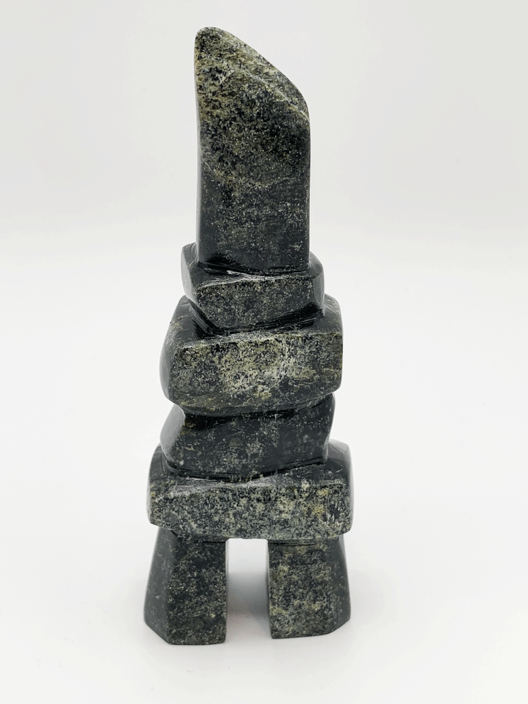 An inukshuk made of five single stones stacked on two legs. The shape very strongly suggests a person shape. The stone is brilliantly mottled green, brown, and black.
