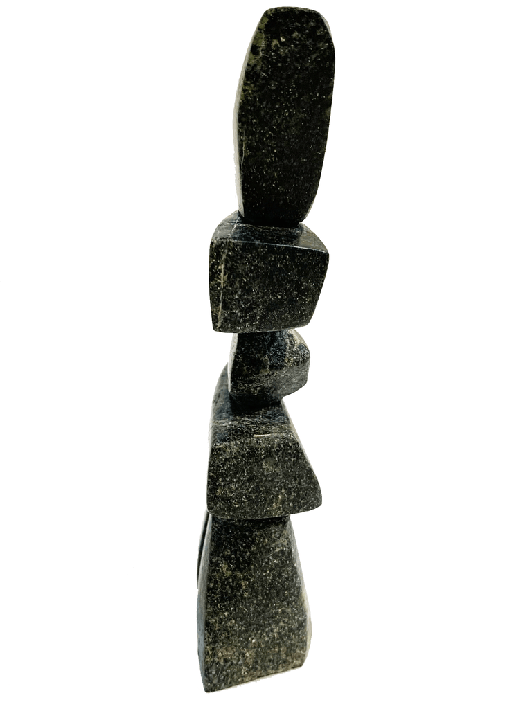 An inukshuk made of four single stones stacked on two legs. The shape very strongly suggests a person shape. The stone is brilliantly mottled green, brown, and black.