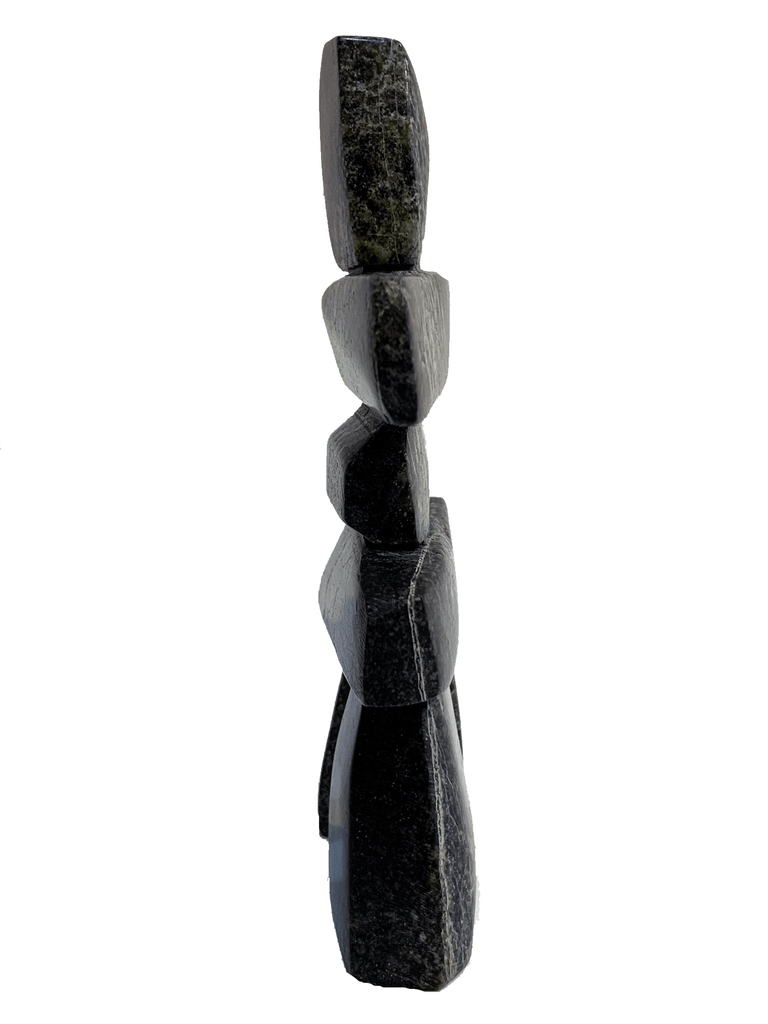 An inukshuk made of four single stones stacked on two legs. The shape very strongly suggests a person shape. The stone is brilliantly mottled green, brown, and black.