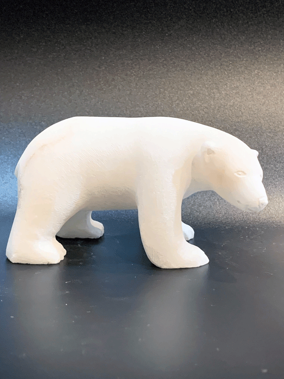 A polar bear carved from white alabaster stands on all fours. The bear's head is tilted, looking cheekily at the viewer. The artist has used a special technique to etch fur texture into the bear for added realism.