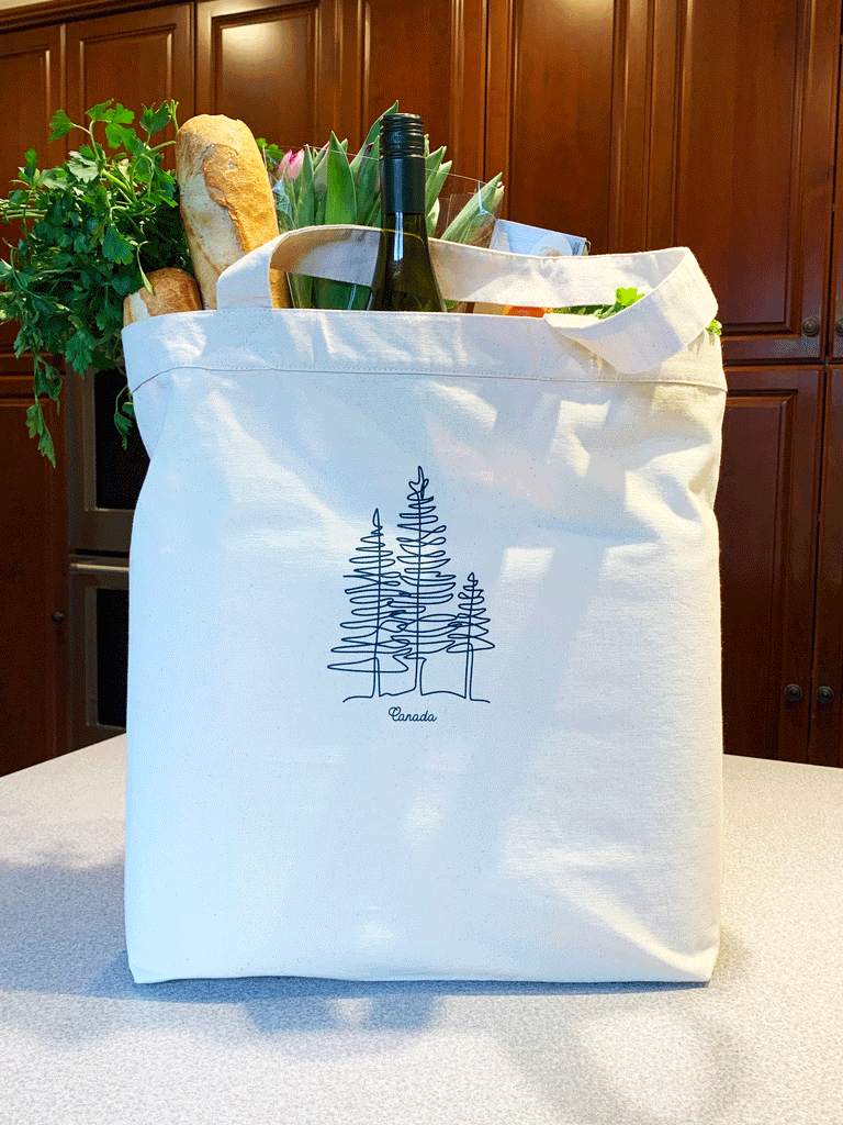 Three pine trees done in a modern line art style in dark blue on a natural canvas bag.