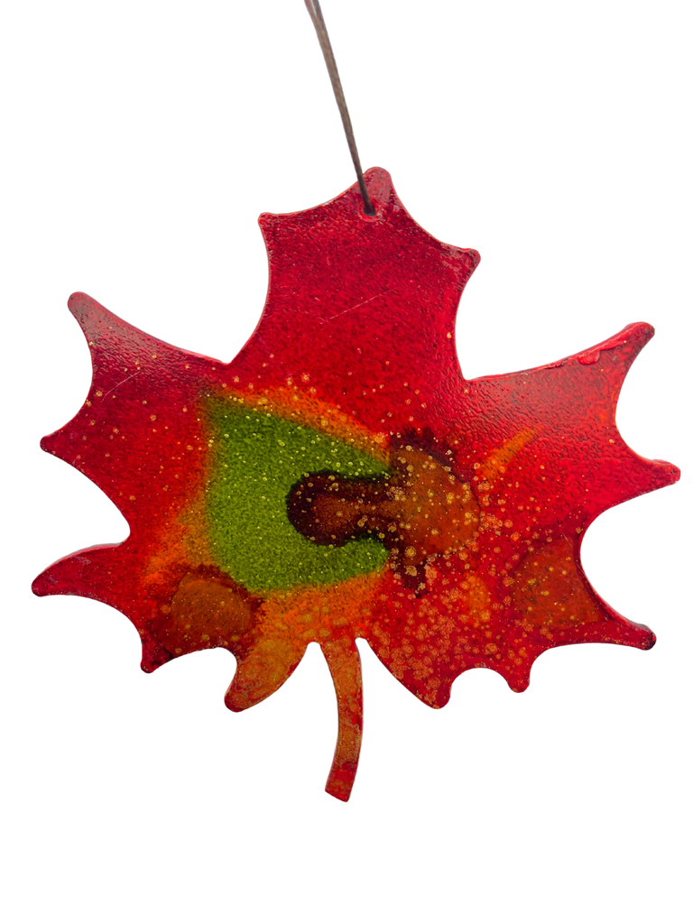 An iconic Canadian maple leaf, cut from steel and handpainted with bold red, green, and gold.