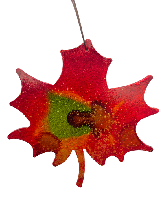 An iconic Canadian maple leaf, cut from steel and handpainted with bold red, green, and gold.