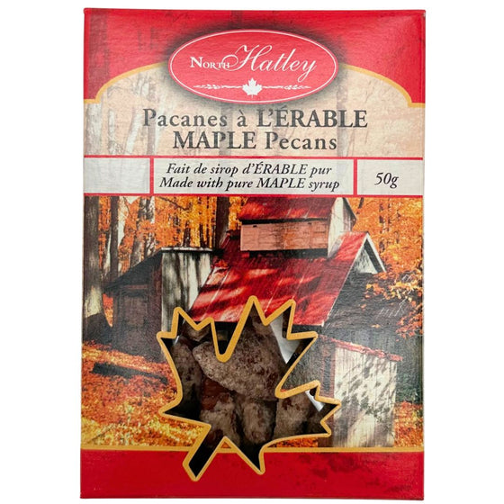 A leaf-shaped window in the packaging shows the maple pecan cookies inside. The box is decorated with an autumn scene of a sugar shack.
