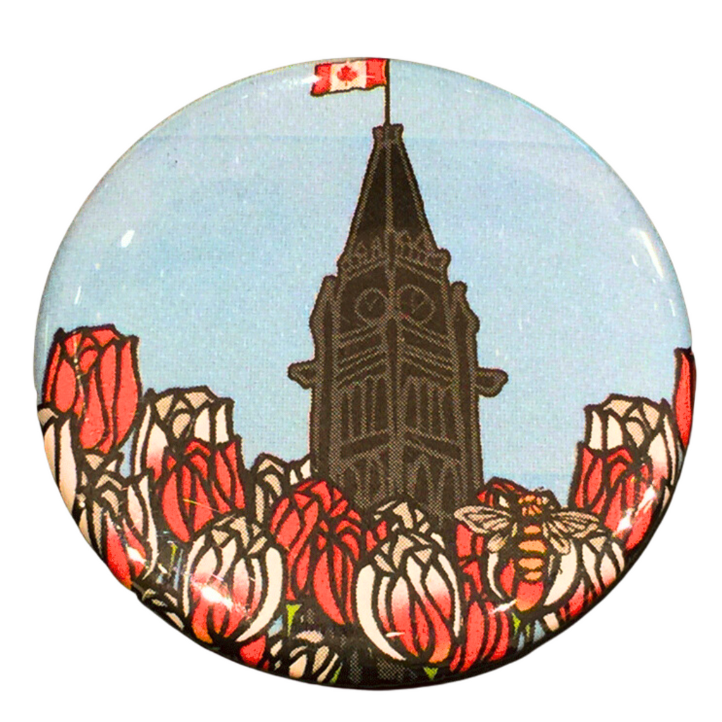 This magnet features an art print of the peace tower and a field of tulips. The peace tower is in the center of the picture and is flying the Canadian flag. The field of flowers has red tulips and Canada 150 tulips, which are white with fiery streaks of red. At the bottom right of the picture is the artists mark—a small picture of a bee.