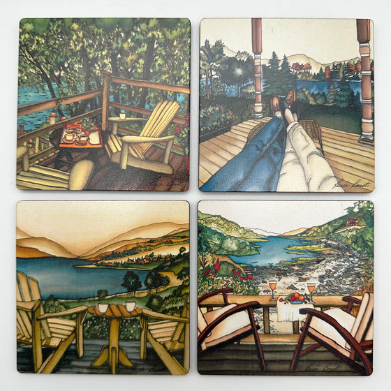 This set of coasters features four unique prints of lakeside cottage decks. One shows a wooden deck with two chairs and a tray of breakfast. One shows two pairs of legs with their feet resting on a stool as if reclining. One shows two Muskoka chairs overlooking the tranquil St Paul’s Bay. One shows two chairs and a spread of fruit and wine overlooking St Paul’s Bay. The pictures are richly coloured. The artist’s signature is at the bottom of each coaster.
