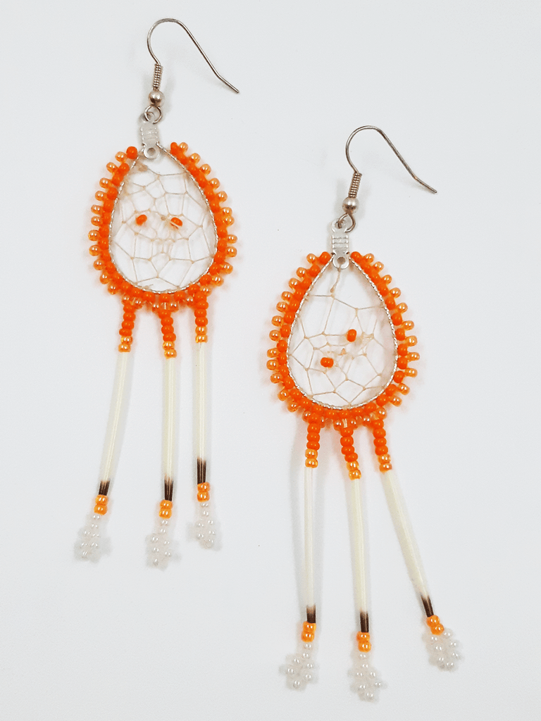 A pair of porcupine quill earrings. The hanging earrings are a tear drop shape hoop with dream catcher style weaving on the inside with orange beads woven into it. Two tones of orange beads are woven along the outside of the hoop and hanging off of the bottom are three strands with dark orange and light orange beads, then a piece of porcupine quill, with light orange and white beads at the end.