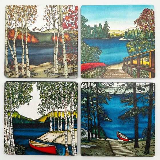 This set of coasters features four unique lakeside art prints. One shows a red canoe on the water surrounded by birch trees. One shows a red canoe docked next to a staircase going uphill. One shows a golden sunset with pine trees beside the lake. One shows birch trees beside a lake in autumn. The pictures are richly coloured. The artist’s signature is at the bottom left of each coaster.