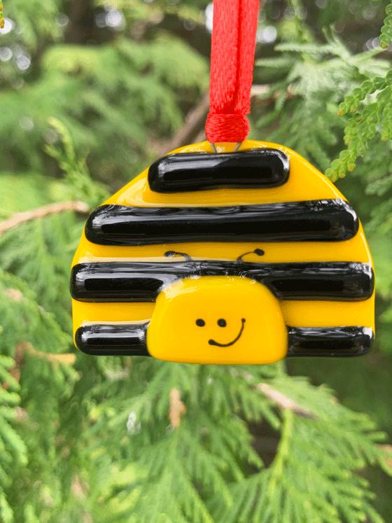 An adorable bee ornament made of fused glass. This Canadian made product is striped yellow and black, displaying a serene smile.