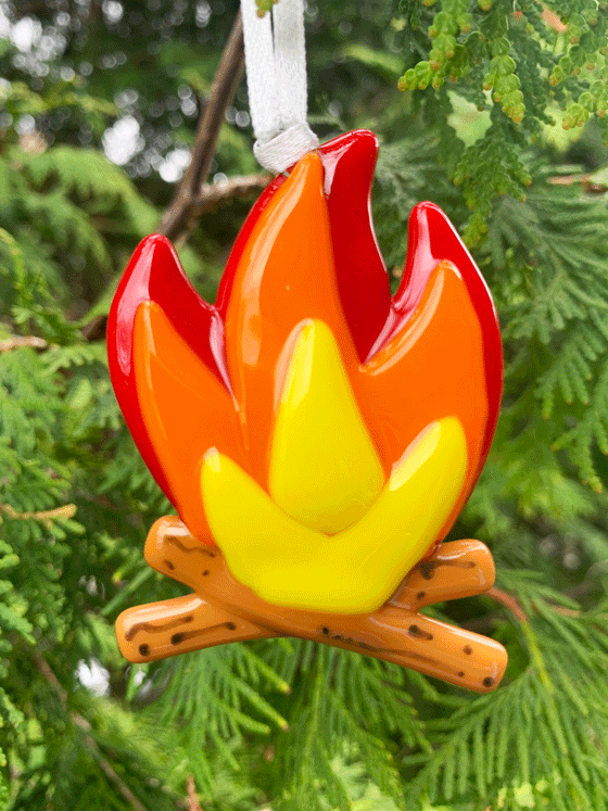 A cheerful Canadian made campfire ornament made from fused glass. This campfire is red, orange, and yellow and rests on top of two logs. 