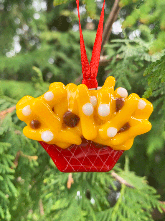 A cute Canadian made fused glass poutine ornament. The yellow fries are supported by a red container at the ornament base. 