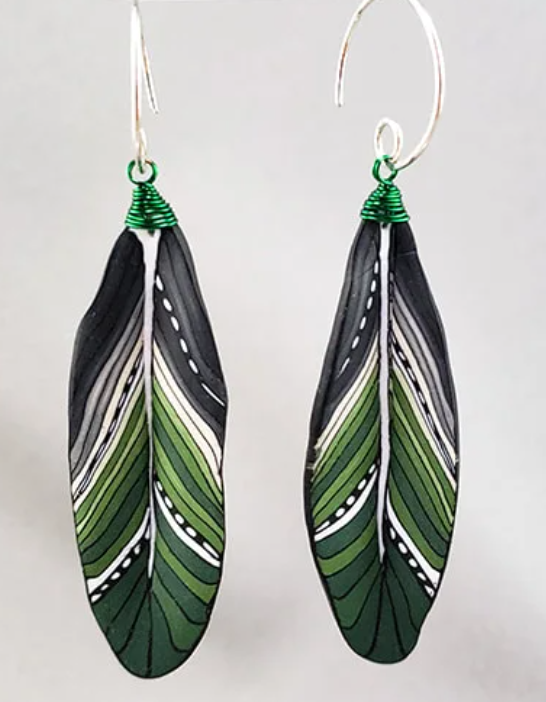Feather-shaped earrings with green, black, and white pattern.