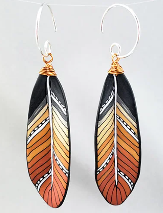 Feather-shaped earrings with black, orange, and white pattern.