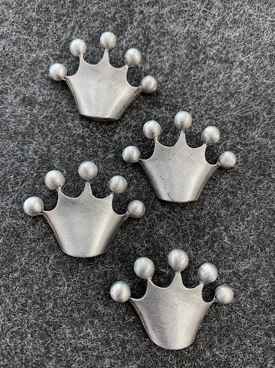 Four pewter magnets in the shape of crowns that come to five points that are topped with circles at the top. 