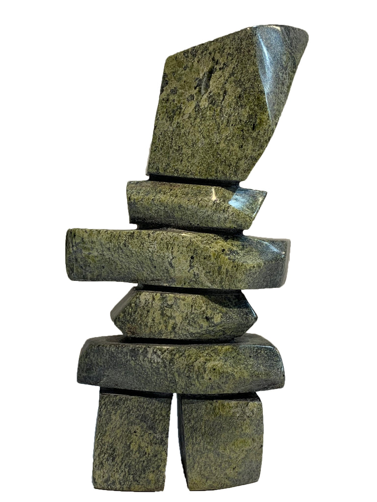 A green and black stone inukshuk. The head is large and bigger on one side.