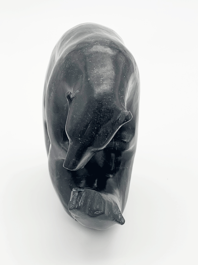 This carved black bear gazes thoughtfully at its reflection, also depicted in sculpture. The two bears stand on each other's four paws. This bear faces the viewer.