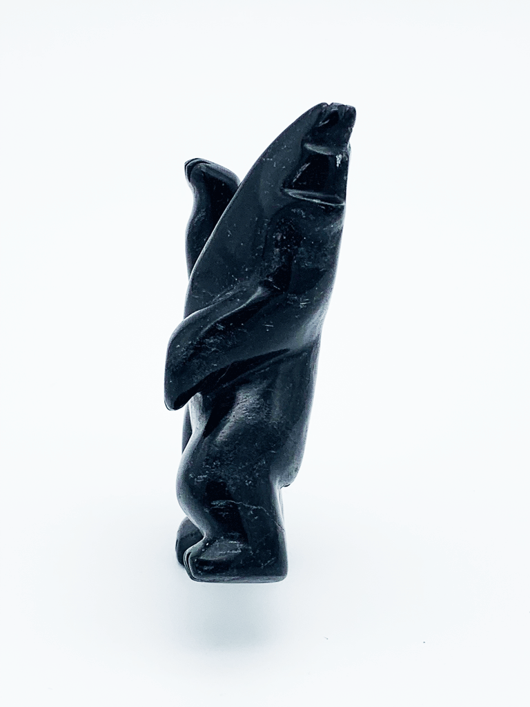 A dancing bear carved from jet black stone. This bear dances on one hind foot, with the other raised to one side and front paws raised. It throws its head back in jubilation. This bear faces left.