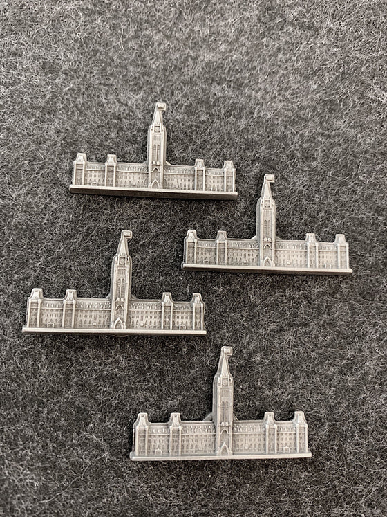 Four pewter magnets in the shape of the Canadian Parliament building with a flag raised on top of the Peace Tower.