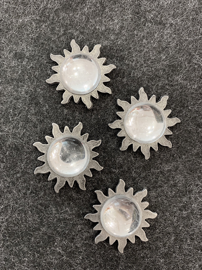 Four pewter magnets in the shape of suns with a glass center. 