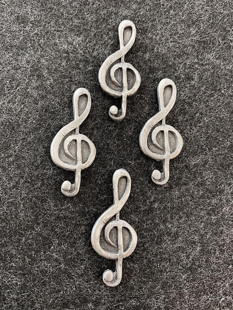 Four pewter magnets in the shape of treble clefs.