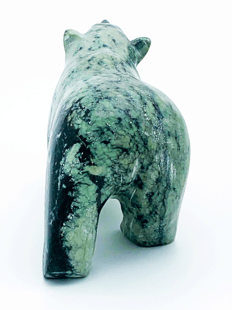 A walking bear carved from vividly contrasting green and black mottled stone. The natural mottling of the stone provides an additional layer of visual interest to the artist's smooth lines and delicate, expressive face. This bear faces away.