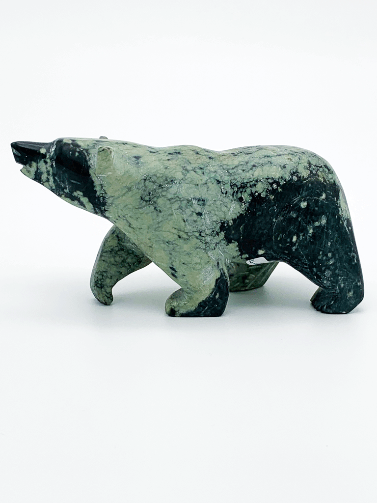 A walking bear carved from vividly contrasting green and black mottled stone. The natural mottling of the stone provides an additional layer of visual interest to the artist's smooth lines and delicate, expressive face. This bear faces left.