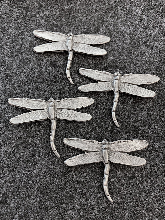 Four pewter magnets in the shape of dragonflies form the top down. 