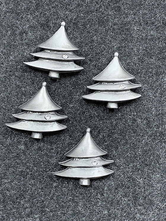 Four pewter magnets in the shape of evergreen trees. A small ball tops the tree, and a a small glass jewel sparkles on the middle branch. 