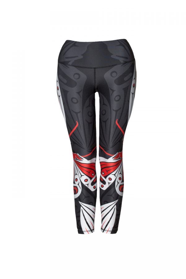 These black, red and white leggings are decorated with two Haida butterflies, one on each leg. The butterflies fly around the outside of the pants toward the front. Part of their wings and antennae can be seen here.