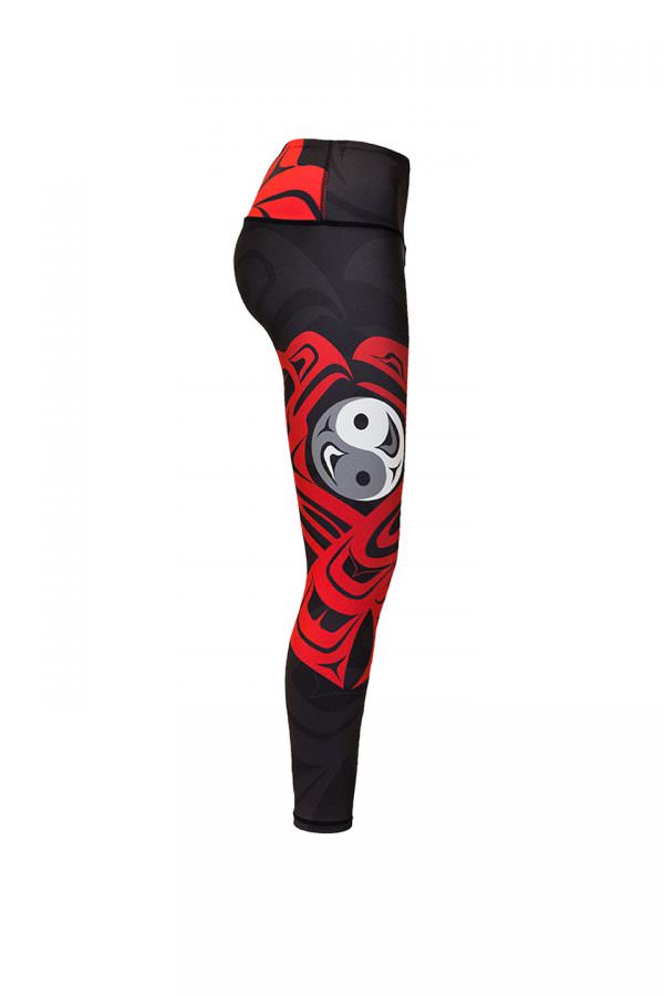 The eagle and raven leggings viewed from the right. This angle provides the clearest depiction of the eagle and raven motif. Eagle is to the left of a yin yang symbol, and raven is to the right. Both birds hold their beaks above the yin yang symbol. Their bodies flow around the yin yang symbol and cross over each other below it. Together, the birds are shaped like a heart.