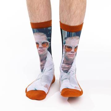 The man, the myth, the legend. These socks feature a close up of Sir Elton John in his famous white jacket and orange sunglasses. 48% Polyester, 45% Cotton, 5% Elastic, 2% Spandex