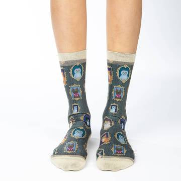 These fun socks feature framed pictures of cats of all shapes and colours hanging on a grey patterned wallpaper. The sole, toe, heel, and rim of the socks are a pale cream colour. The active fit socks sport elastic arch bands to contour to your feet and provide support.