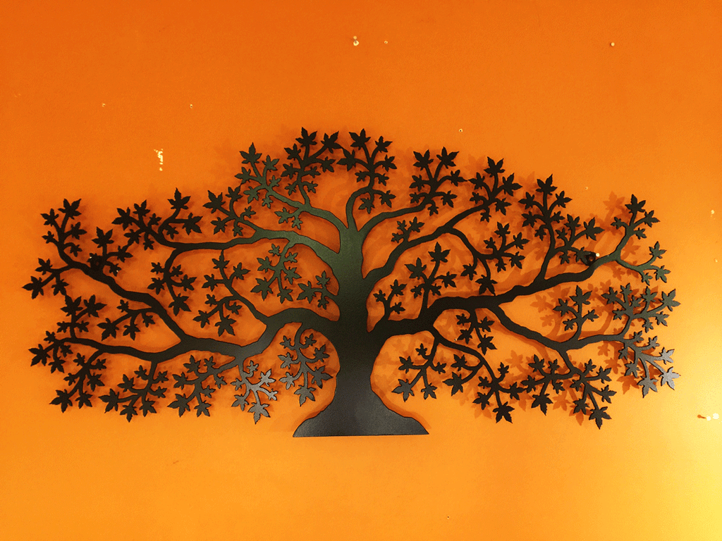 A matte black wall mounted maple tree on an orange wall.