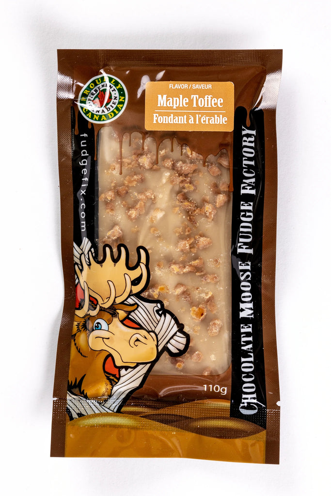 Rectangular Fudge Bar made in Canada Inside of a plastic package. There is a cartoon Moose on the cover of the package, and big writing saying 'Chocolate Moose Fudge Factory'. Flavor of the fudge is labeled Maple Toffee. Fudge is light brown maple with small pieces of toffee on top of it.