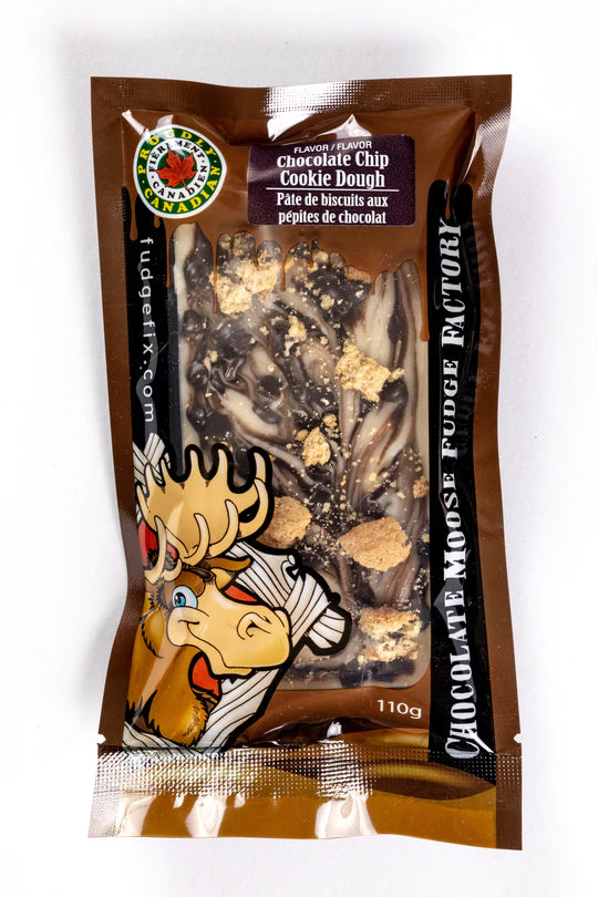 Rectangular Fudge Bar made in Canada Inside of a plastic package. There is a cartoon Moose on the cover of the package, and big writing saying 'Chocolate Moose Fudge Factory'. Flavor of the fudge is chocolate chip cookie dough. Fudge is brown and white with pieces of cookies on top of it. 
