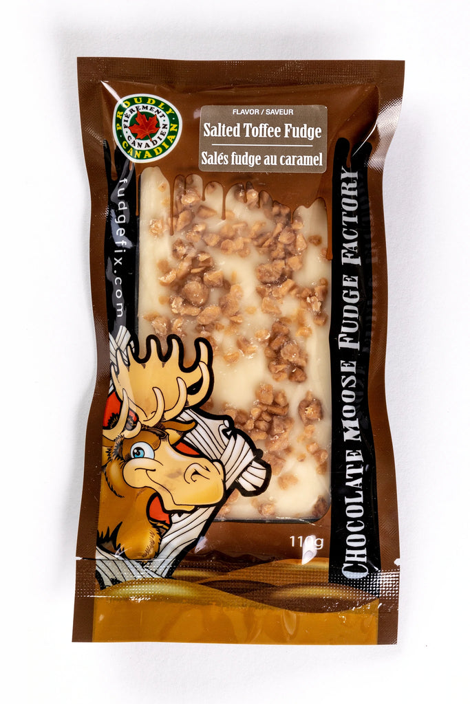 Rectangular Fudge Bar made in Canada Inside of a plastic package. There is a cartoon Moose on the cover of the package, and big writing saying 'Chocolate Moose Fudge Factory'. Flavor of the fudge is labeled Salted Toffee. Fudge is white and light brown with pieces of toffee caramel on top of it.