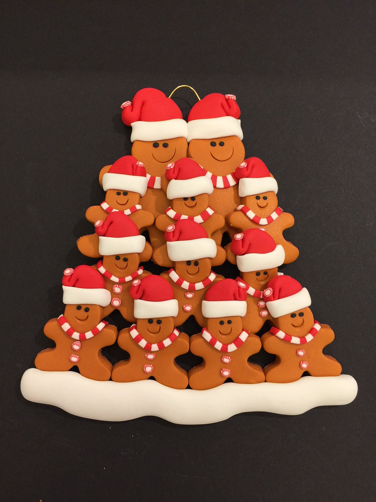 Two smiling gingerbread men stand side by side wearing a red Santa hat, red and white mints as buttons, and a red and white striped scarf. Ten similarly dressed gingerbread children stand in front of the larger figures.