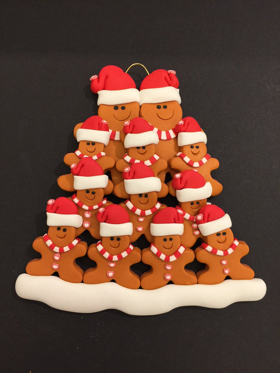 Two smiling gingerbread men stand side by side wearing a red Santa hat, red and white mints as buttons, and a red and white striped scarf. Ten similarly dressed gingerbread children stand in front of the larger figures.