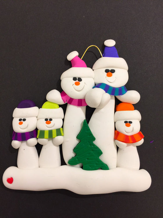 A family of five happy snowmen. The large snowmen hold hands and are dressed in pink and blue hats and scarves. The smaller snowmen wear purple, green, and orange. In front of the group sits a small Christmas tree.