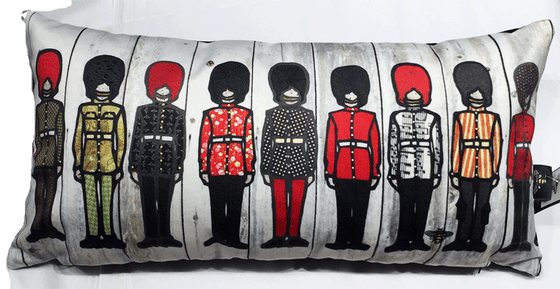 This large pillow features nine soldiers in ceremonial outfits. Each soldier wears long pants, a belted jacket, and a tall beefeater hat. Each jacket has a unique colourful print on it—for example, polka dots, flowers, stripes or sheet music. At the bottom right of the pillow is the artists mark—a small picture of a bee.