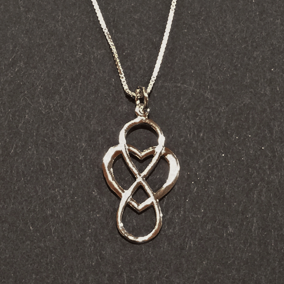A sterling silver infinity symbol intertwined with a heart hang from a silver chain. The infinity symbol is placed vertically so it resembles an eight. The chain attaches to the top of the infinity symbol.