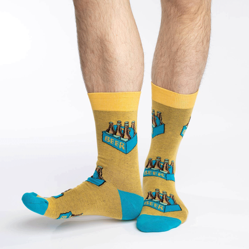 These fun socks feature six beer bottles in a blue cardboard carrying box with the word “BEER” written on the side. The boxes are on top of a dark yellow background, with blue heels and toe, and bright yellow rim. Spandex added to the 85% cotton blend gives the socks the perfect amount of stretch to hug your feet.