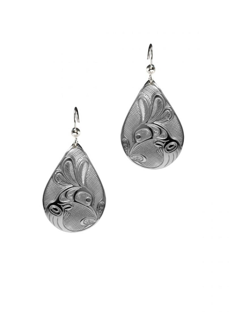 Silvery teardrop shaped earrings with a Haida design of a hummingbird drinking from a flower.