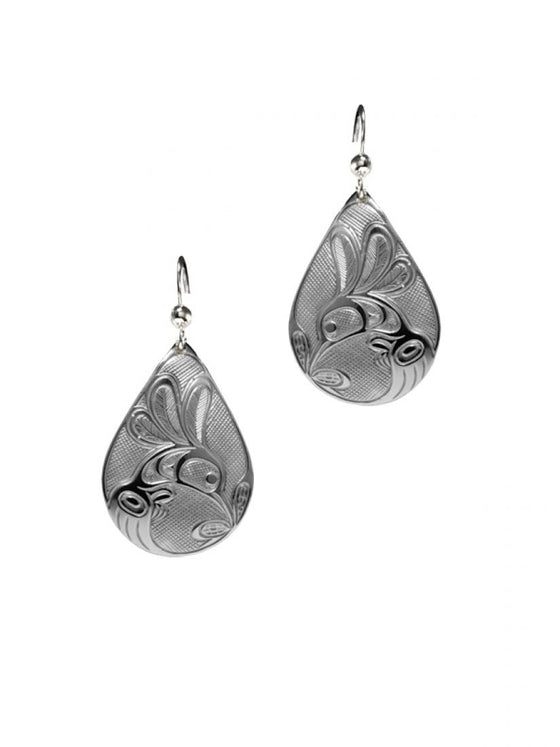Silvery teardrop shaped earrings with a Haida design of a hummingbird drinking from a flower.