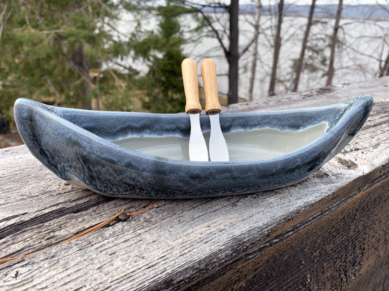 A stoneware canoe grey-green on the bottom and a mottled grey rim. Includes two paddle spreaders.