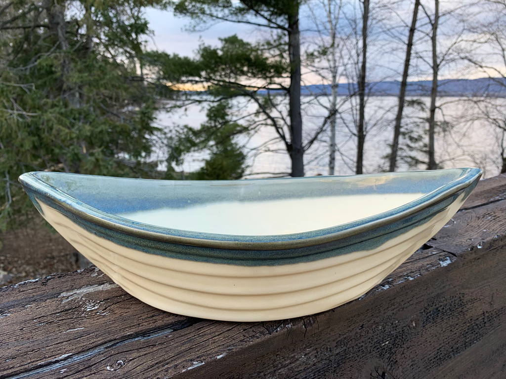 A grey and cream pottery boat with pointed ends, about the size of a small mixing bowl.