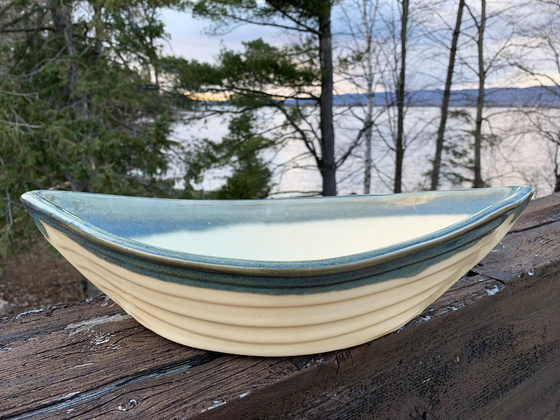 A grey and cream pottery boat with pointed ends, about the size of a small mixing bowl.