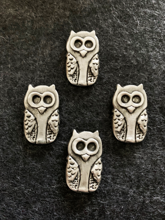 Four pewter magnets in the shape of cute owls with large eyes and small pointed ears.